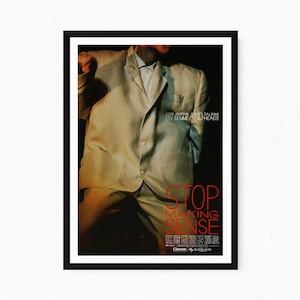 Könnte beinhalten: Ein gerahmtes Filmplakat für Stop Making Sense mit einer Person in einem übergroßen hellen Anzug. Der Text lautet A FILM BY JONATHAN DEMME AND TALKING HEADS, STOP MAKING SENSE, und enthält verschiedene Produktionskredite am unteren Rand.