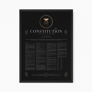 May include: A framed black poster featuring the text The Constitution of the United States of America in white and gold lettering. The design includes a central gold emblem, decorative corner motifs, and columns of small text detailing the articles.