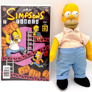 May include: A Simpsons Comics #161 comic book and a Homer Simpson plush doll. The comic book cover features Homer Simpson, Lisa, and Bart Simpson with a pink and black background. The Homer Simpson doll is wearing a white shirt, blue pants, and black shoes.