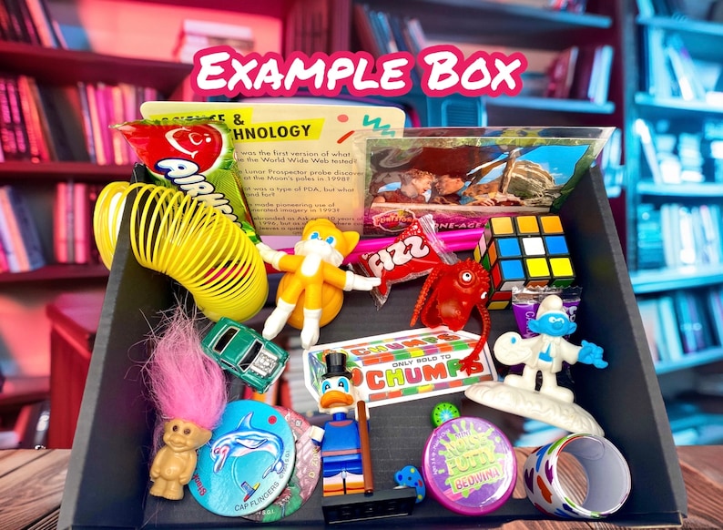 May include: A black box filled with assorted retro toys and sweets, including a yellow spring, a small green car, a troll doll with pink hair, a Rubik's cube, a Smurf figurine, a Donald Duck figure, a dolphin disc, and various snack packages.