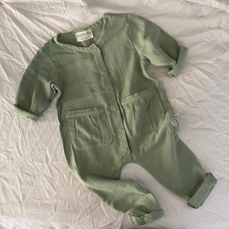 Handmade sage green baby romper made from soft organic muslin cotton. Breathable and stylish long-sleeve one-piece outfit for babies and toddlers – gender-neutral boho baby gift idea.