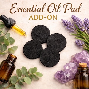 May include: An image featuring four black essential oil pads, a dropper with yellow liquid, and a brown essential oil bottle. The words "Essential Oil Pad ADD-ON" are displayed in brown script. Lavender and amethyst crystals are also present.