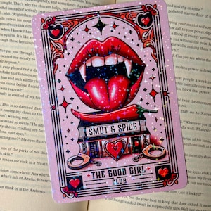 May include: Pink, glittery card with a vampire mouth, chili peppers, and the text "SMUT & SPICE" and "THE GOOD GIRL CLUB." The card has hearts, handcuffs, and star accents.