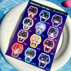 May include: A sheet of stickers featuring cartoon characters with different coloured backgrounds and text. The text includes "MANHWA/HUA NVI" and names like "KDJ", "YJH", "HSY", "CXS", "LG", "QL", "HYJ", "SHJ", "HYH", "Cale", "CEJ", and "LSV".