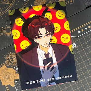 Puede incluir: Impresión rectangular con una ilustración de estilo anime de un hombre con traje sosteniendo un teléfono. El fondo es rojo con caras sonrientes amarillas. El texto en la parte inferior está en coreano.