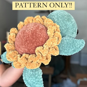 Pode incluir: Uma tartaruga de crochê com um design floral. O corpo da tartaruga é turquesa, e a flor é laranja e coral. O texto "FRANKIE THE FLOWER TURTLE PATTERN ONLY!!" é exibido acima da tartaruga.