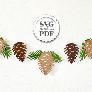May include: A garland featuring paper cutouts of pine cones and green pine needles. The pine cones are in shades of brown and tan. The garland is strung on a thin white string. A white circular emblem with the text "SVG and PDF" is at the top.