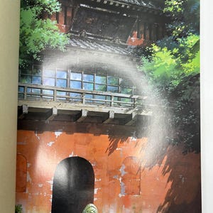 May include: An illustration of a traditional Japanese building with a red-orange wall and a dark roof. Lush green foliage surrounds the structure, with a stone statue in the foreground. The building has a large arched entrance.