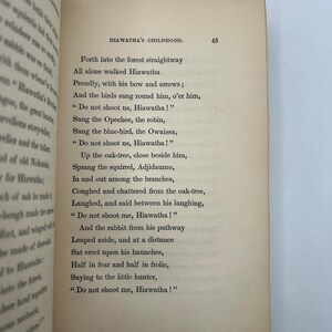 May include: Open book with text from "Hiawatha's Childhood" on a cream-colored page. The text includes lines like "Do not shoot us, Hiawatha!" and is set in a classic serif font. The page number 45 is visible.