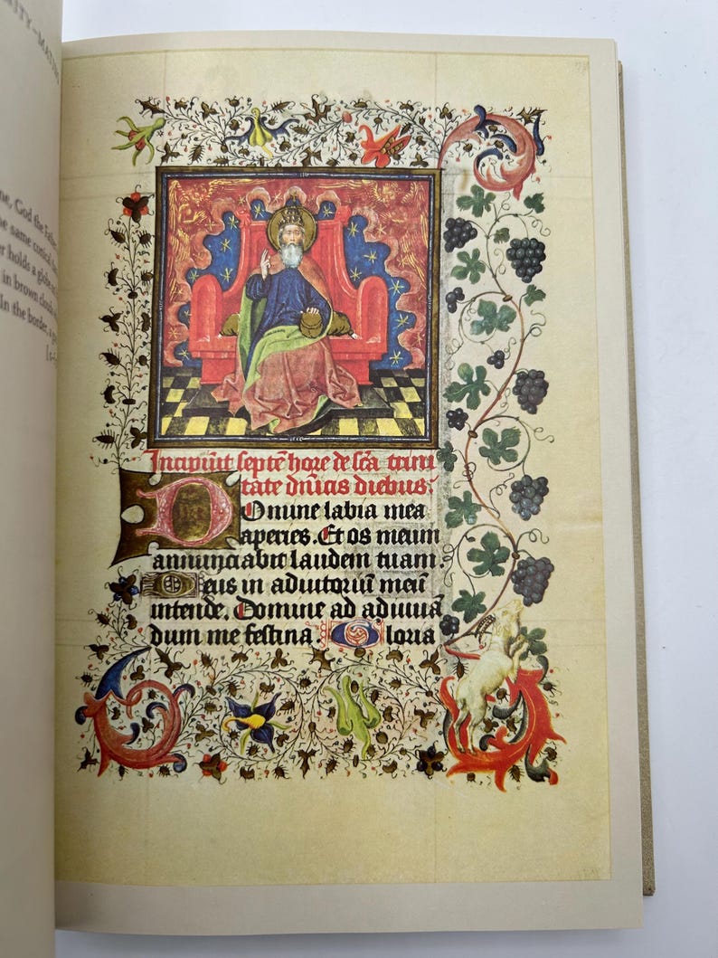 May include: An illuminated manuscript page featuring a detailed illustration of a seated figure in a red throne, surrounded by ornate floral and foliate borders. The page includes Latin text and decorative elements in red, blue, and gold.