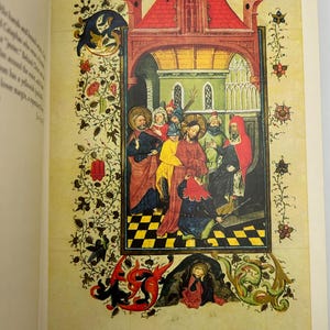 May include: A detailed illustration from a medieval manuscript. The artwork depicts a religious scene with figures in colorful robes, set within an ornate architectural frame. The page is bordered with floral and foliate designs, and the background is a parchment color.