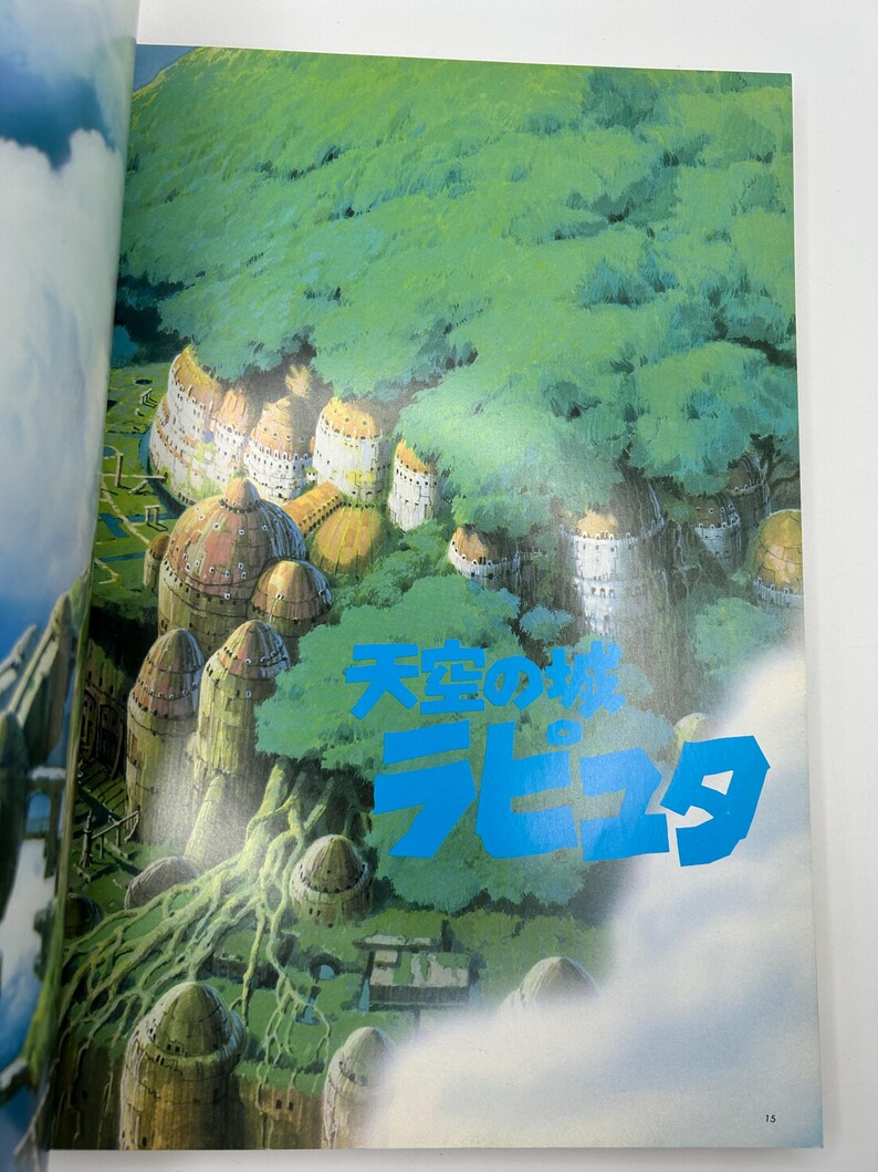 May include: A page from a book featuring a vibrant illustration of a fantasy landscape. The image showcases a floating city with domed structures nestled among lush green foliage. The text "Laputa" is displayed in blue.