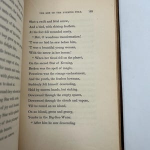 May include: Open book with aged, yellowed pages. The text on the right page is titled "THE SON OF THE EVENING STAR" and includes poetry. The book's spine is dark brown, and the edges of the pages are rough.