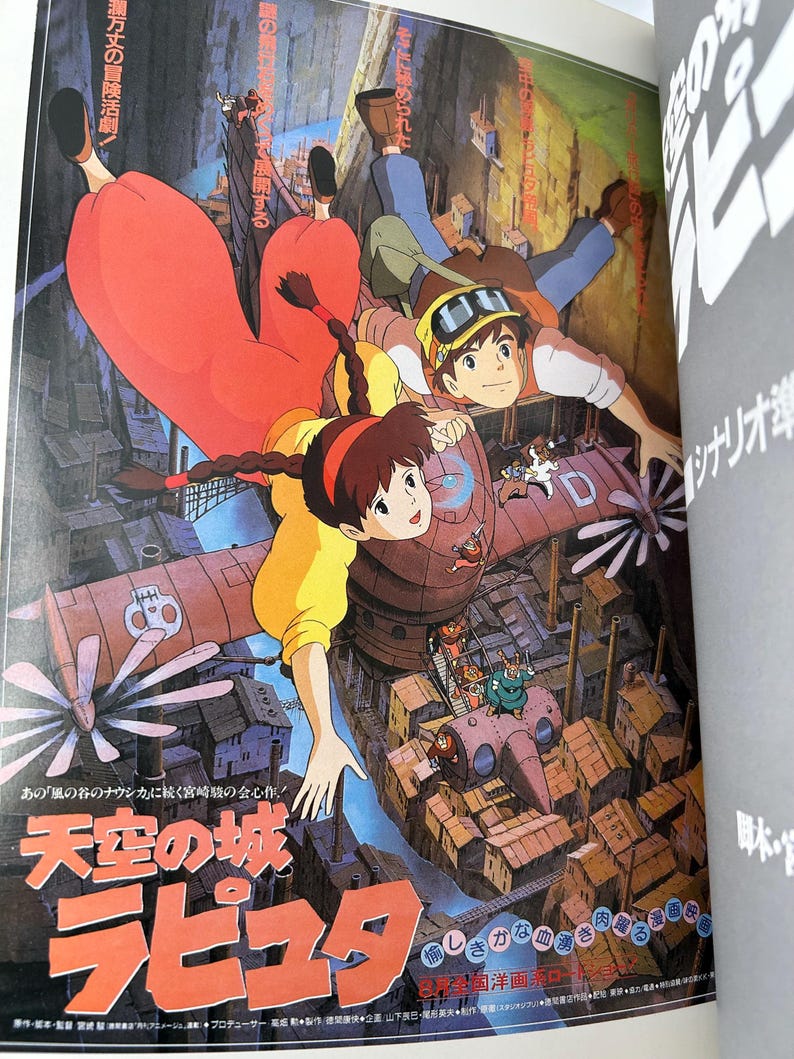 May include: A vibrant illustration from the animated film "Castle in the Sky" featuring characters in flight over a city. The artwork showcases a detailed cityscape with a red airship and Japanese text. The color palette includes shades of red, yellow, and blue.
