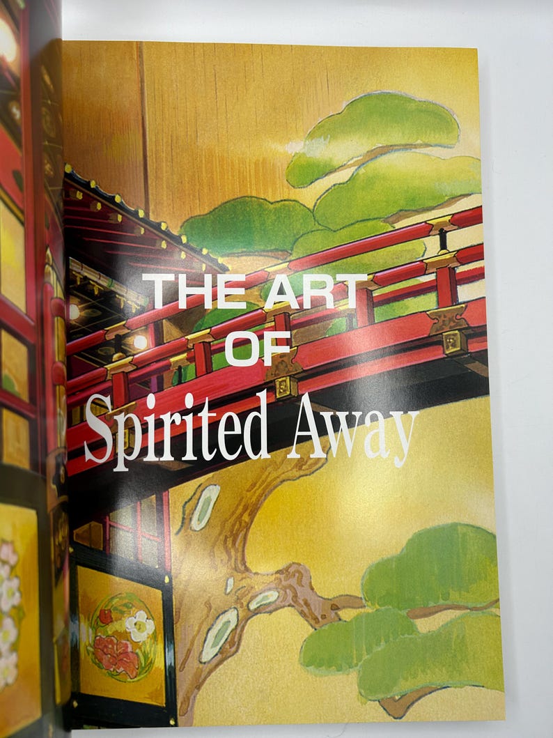 May include: A book cover featuring the title "THE ART OF Spirited Away" in white text. The cover art depicts a red bridge with black accents, green foliage, and a gold background. The book is open.