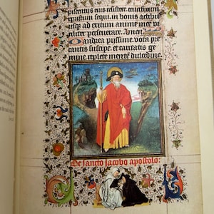 May include: An open book displaying a page from a medieval manuscript. The page features ornate floral borders, text, and a central illustration of a figure in red robes. The text includes the words "De Jando lambo apoltolo:"