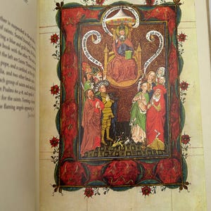 May include: A page from a book featuring a medieval illustration. The artwork depicts a seated figure with a halo, surrounded by other figures in colorful robes. The illustration is framed with a red border and floral accents.