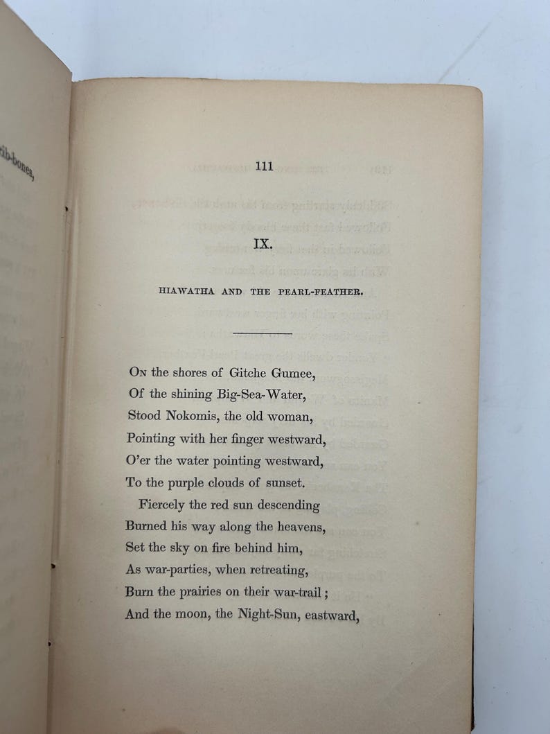 May include: Open book with text from the poem "Hiawatha and the Pearl-Feather". The page number 111 is visible. The text is in black ink on aged, off-white paper. The book is open to a poem.