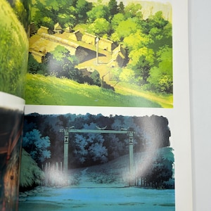 May include: A book page featuring two illustrations from Princess Mononoke. The top image shows a village with thatched-roof buildings in a forest. The bottom image depicts a wooden gate at night. Japanese text is printed at the top right corner.