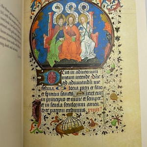 May include: A page from a medieval illuminated manuscript. The image features a central oval with three figures, surrounded by ornate floral and foliate borders. The text in Latin is visible below the illustration.