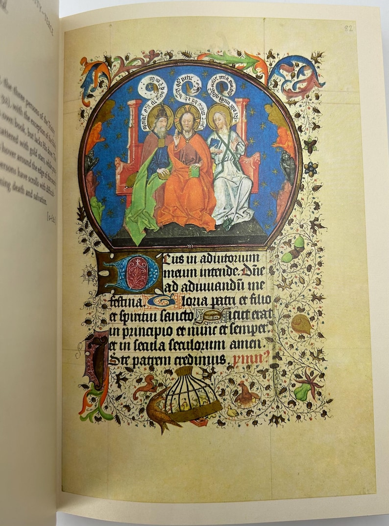 May include: A page from a medieval illuminated manuscript. The image features a central oval with three figures, surrounded by ornate floral and foliate borders. The text in Latin is visible below the illustration.