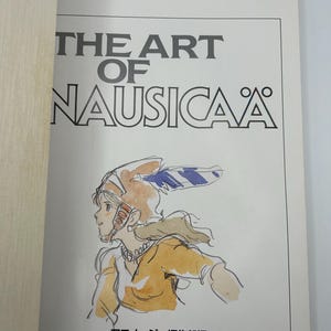 May include: A book titled "THE ART OF NAUSICA&Auml;" with a drawing of a character in a helmet and yellow clothing. The book's title is in large, bold, black letters. The text "THE ART OF NAUSICA&Auml;" is at the top of the page.