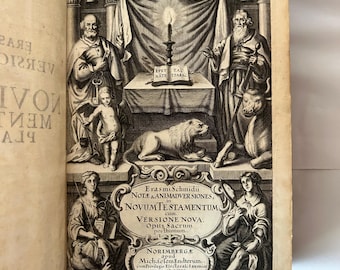 May include: An open book with detailed black and white illustrations. The top half features figures, a table with a candle, and an eagle. The bottom half displays text in ornate lettering, including "NOVUM TESTAMENTUM".