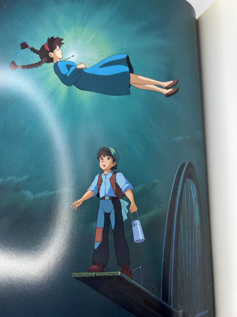 May include: Illustration from an animated film featuring two characters. A woman in a blue dress floats in a bright light. Below, a young man stands on a wooden platform, holding a container. The background is a dark blue.