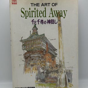 May include: A book titled "THE ART OF Spirited Away" with Japanese text and an illustration of a building and a tall structure. The cover is off-white with green and brown text and illustrations.
