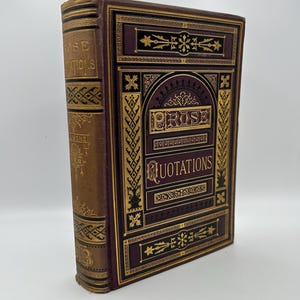 Könnte beinhalten: Ein burgunderfarbenes Buch mit goldenen und schwarzen Akzenten. Der Titel auf dem Einband lautet "Prose Quotations".