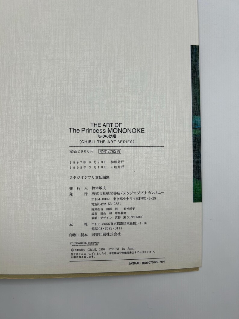 May include: A white page from The Art of The Princess Mononoke book featuring black printed text in English and Japanese. The text includes the title, series name, publication dates, and publisher information for Studio Ghibli, with a dark green edge.