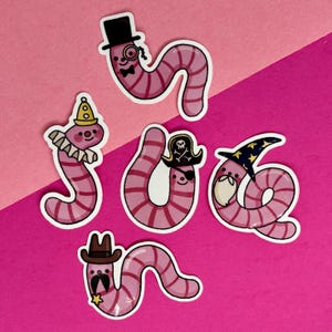 May include: A collection of whimsical worm stickers. Each worm is pink with darker pink stripes and a white outline. The worms are dressed as a gentleman, clown, pirate, wizard, and cowboy, set against a pink background.
