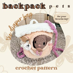 May include: A crocheted peach-colored backpack with a white top flap and pink straps. A small brown plush animal sits inside the main compartment, holding a pink pacifier. A wooden clip with a round white tag labeled "K the kitty" is attached.