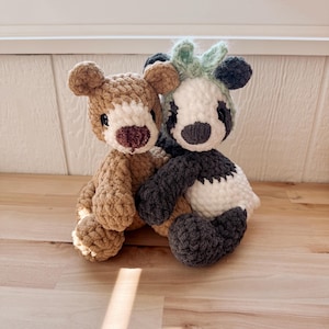 May include: Two handmade crochet stuffed animals: a brown bear and a panda. The bear has a light brown body, a darker brown nose, and black eyes. The panda has a black and white body with a green tuft of hair.