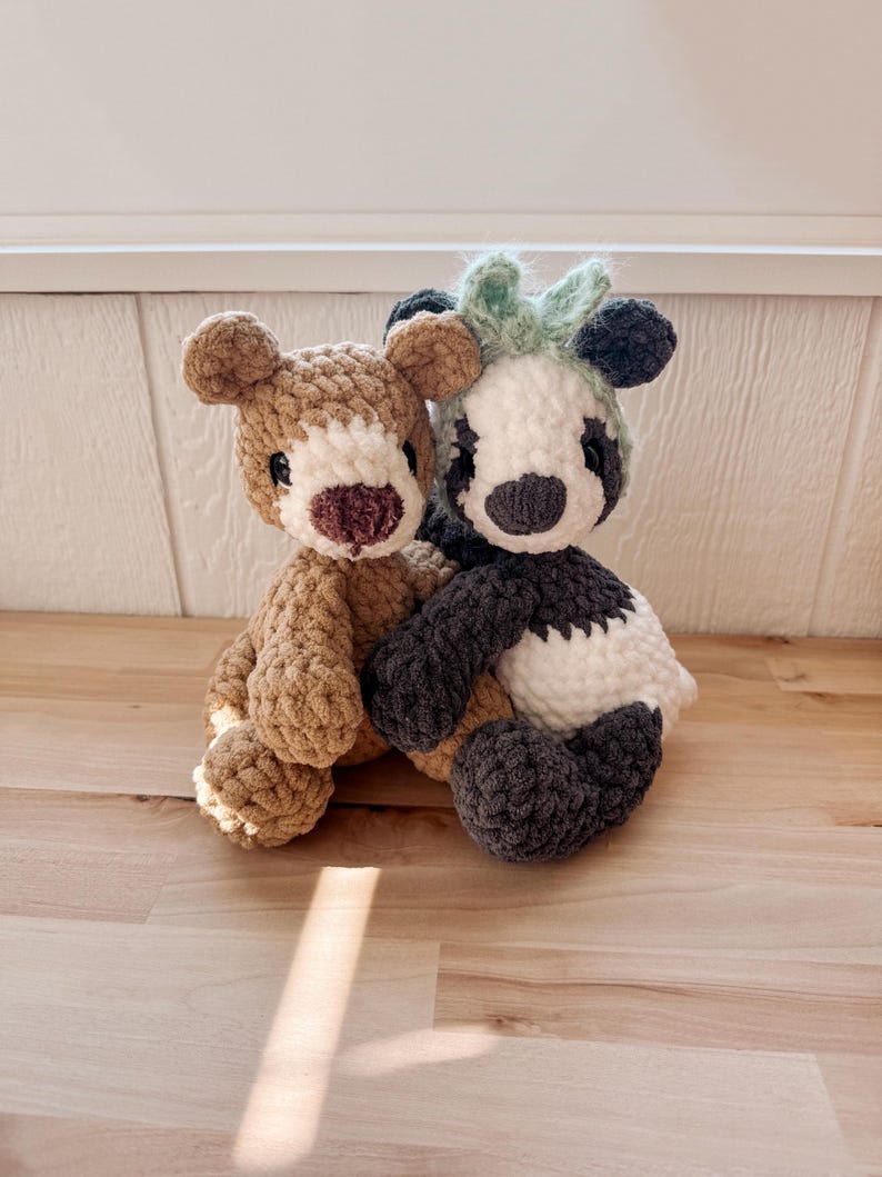 May include: Two handmade crochet stuffed animals: a brown bear and a panda. The bear has a light brown body, a darker brown nose, and black eyes. The panda has a black and white body with a green tuft of hair.