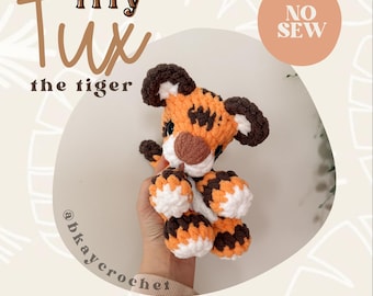 May include: A crocheted tiger toy in shades of orange, brown, and white. The tiger has a round head, small ears, and a tan nose. The image includes the text "itty Tux the tiger" and "crochet pattern".