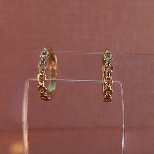 May include: A pair of gold hoop earrings with a chain link design.