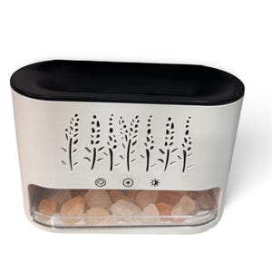 May include: A white rectangular diffuser with a black top lid and a clear lower compartment filled with small, rough-cut pink Himalayan salt rocks. The front panel features a laser-cut floral pattern and three circular control icons below it.