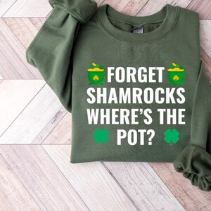 May include: A green sweatshirt with the text "Forget Shamrocks Where's the Pot?" in white. The text is surrounded by small shamrock and pot of gold graphics.