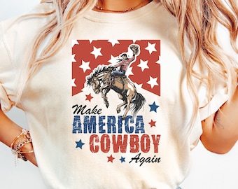 Peut inclure: Un t-shirt blanc avec un graphique d'un cowboy chevauchant un cheval cabré. Le graphique est entouré d'étoiles rouges et du texte "Make America Cowboy Again".