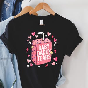 May include: A white ceramic mug with a black handle and the text "But First, Coffee" in a handwritten style. The mug is on a white surface. The mug is likely for hot beverages.