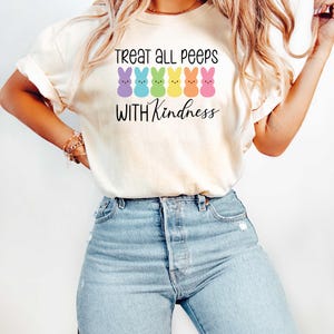 May include: A white t-shirt with a graphic of a row of colorful Peeps candy and the text "Treat all peeps with kindness".