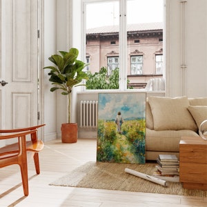 Puede incluir: Una pintura de una persona caminando por un sendero a trav&eacute;s de un campo de flores. La pintura est&aacute; enmarcada en un marco dorado y est&aacute; colgada en una pared blanca. La pintura est&aacute; en una sala de estar con un sof&aacute; y una silla.