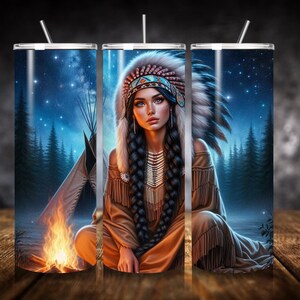 Può includere: Un bicchiere in acciaio inossidabile con un design di una donna nativa americana che indossa un copricapo e abiti tradizionali. Lo sfondo è un cielo notturno stellato con un falò in primo piano.