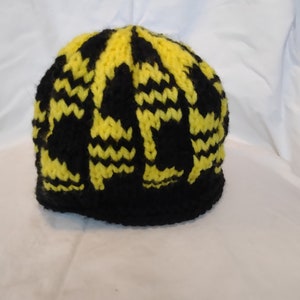 Puede incluir: Gorro de punto negro y amarillo con un patrón de chevron.