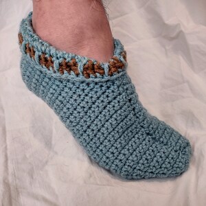 May include: A pair of blue crocheted slipper socks with a brown crocheted trim around the top.