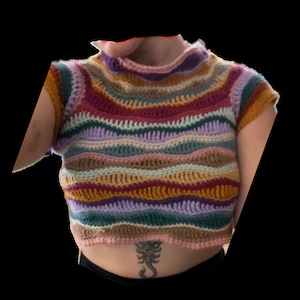 May include: A colorful striped crochet top with a high neckline and short sleeves. The top is made with a variety of colors, including pink, purple, green, blue, and brown.