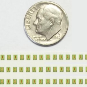 May include: A sheet of green and red stickers with the number "1" printed on each sticker. The stickers are arranged in three rows of ten stickers each. A dime is shown for scale.