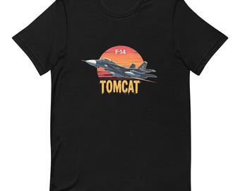 May include: Black t-shirt featuring a graphic of an F-14 Tomcat fighter jet in flight against a sunset backdrop. The word "TOMCAT" is printed in a bold, yellow font below the aircraft. The shirt is made of a soft material.