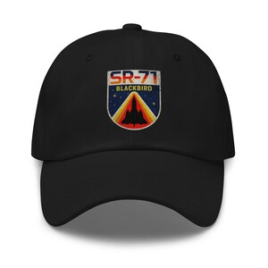 May include: Black baseball cap featuring a vintage-style SR-71 Blackbird patch. The patch includes the text "SR-71 BLACKBIRD" with a silhouette of the aircraft against a starry sky, framed by a retro color scheme.